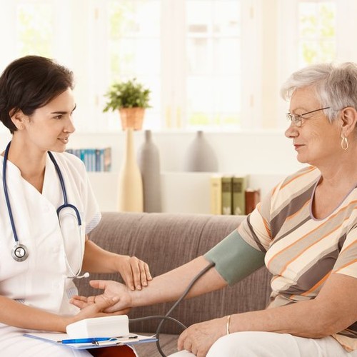 Eine Altenpflegerin misst bei einer Frau den Blutdruck.