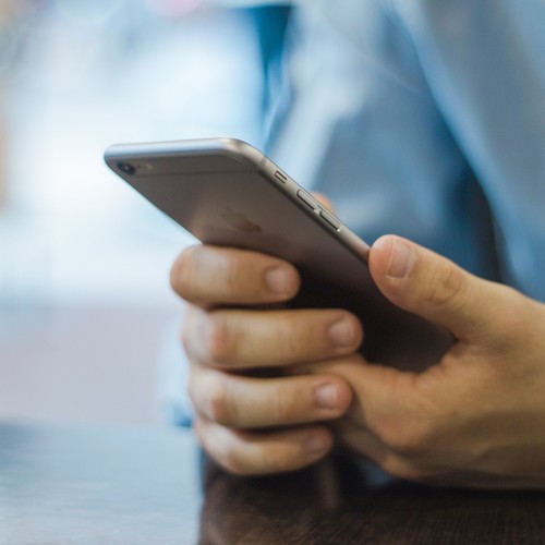 Ei Mann hält ein Smartphone in beiden Händen
