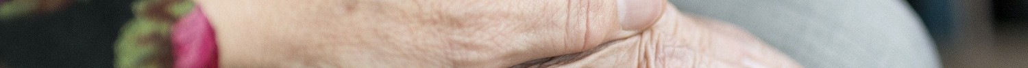 Eine Hand legt sich schützend über die Hand eines älteren Menschen