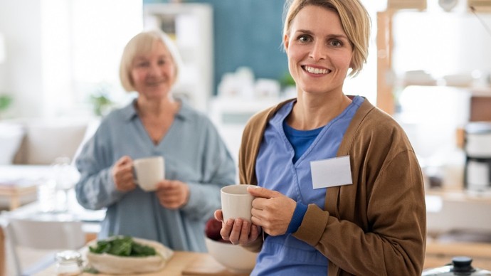 Zwei Frauen halten eine Kaffeetasse in der Hand und schauen in die Kamera